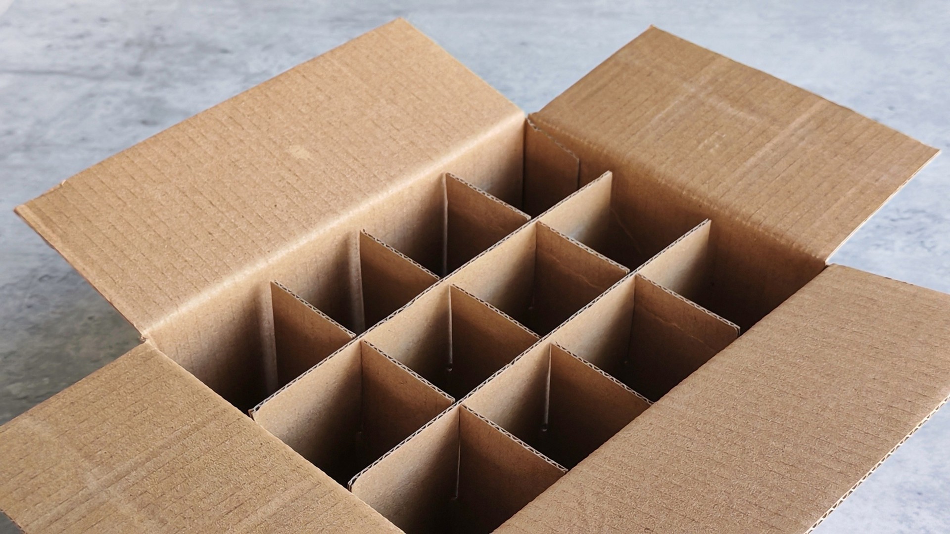 Open Cardboard Box with Dividers on Concrete Surface, Ideal for Secure Packaging and Organized Storage